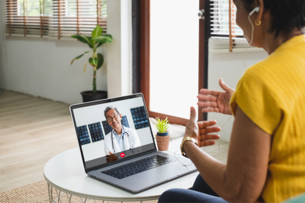 Woman speaking virtually with male asian doctor on laptop